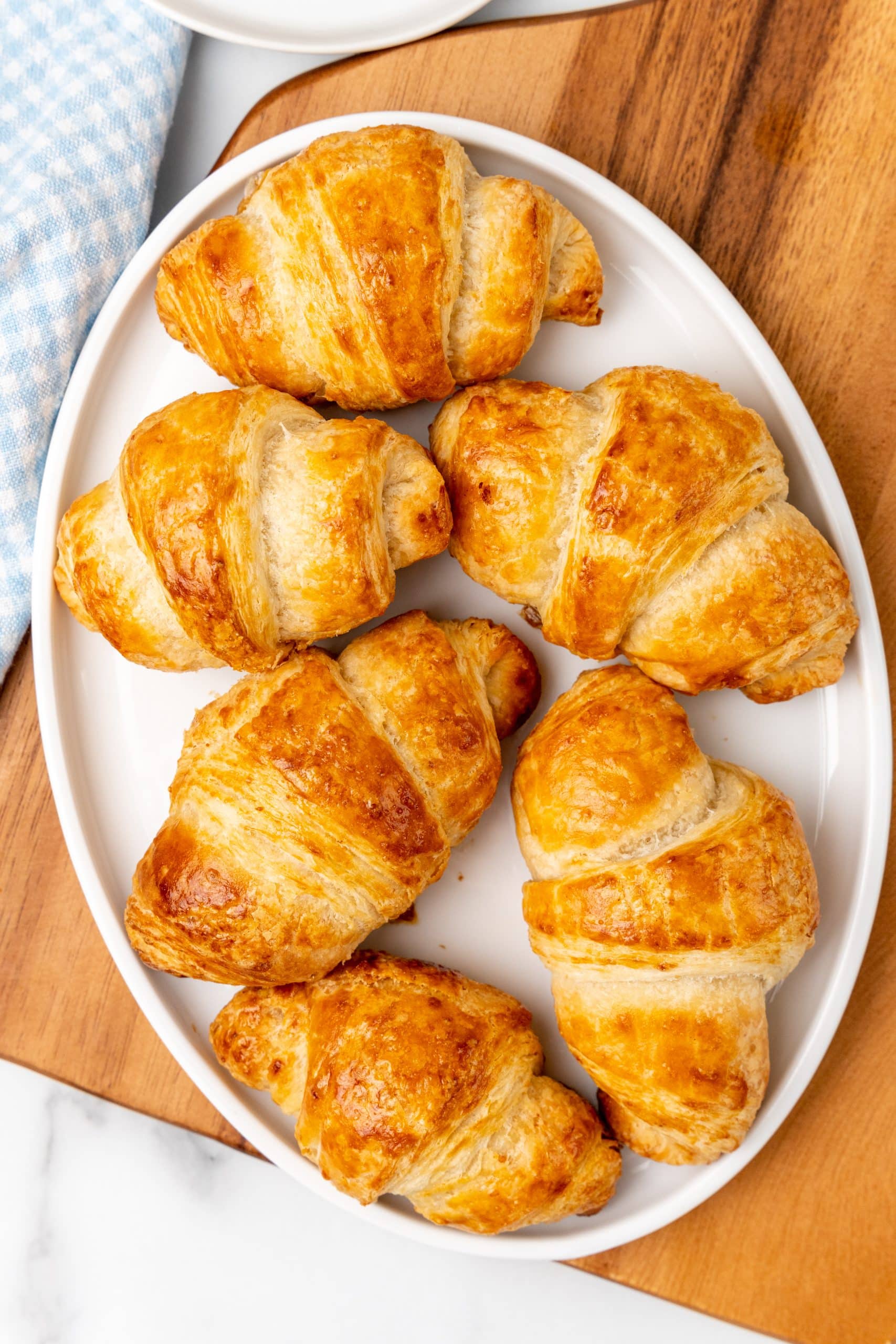 homemade butter croissants stacked on a white plate