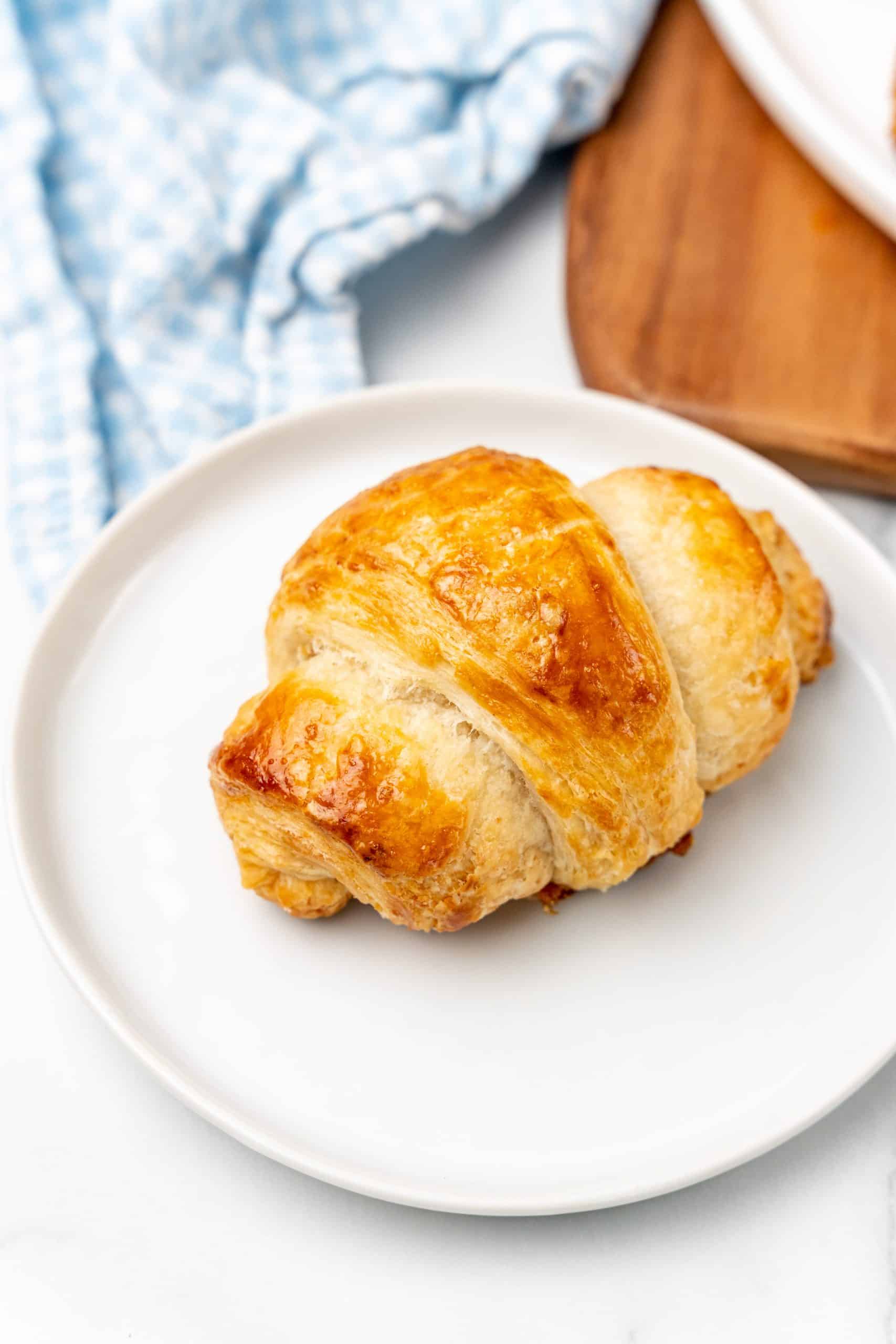 a baked buttery homemade croissant on a white plate