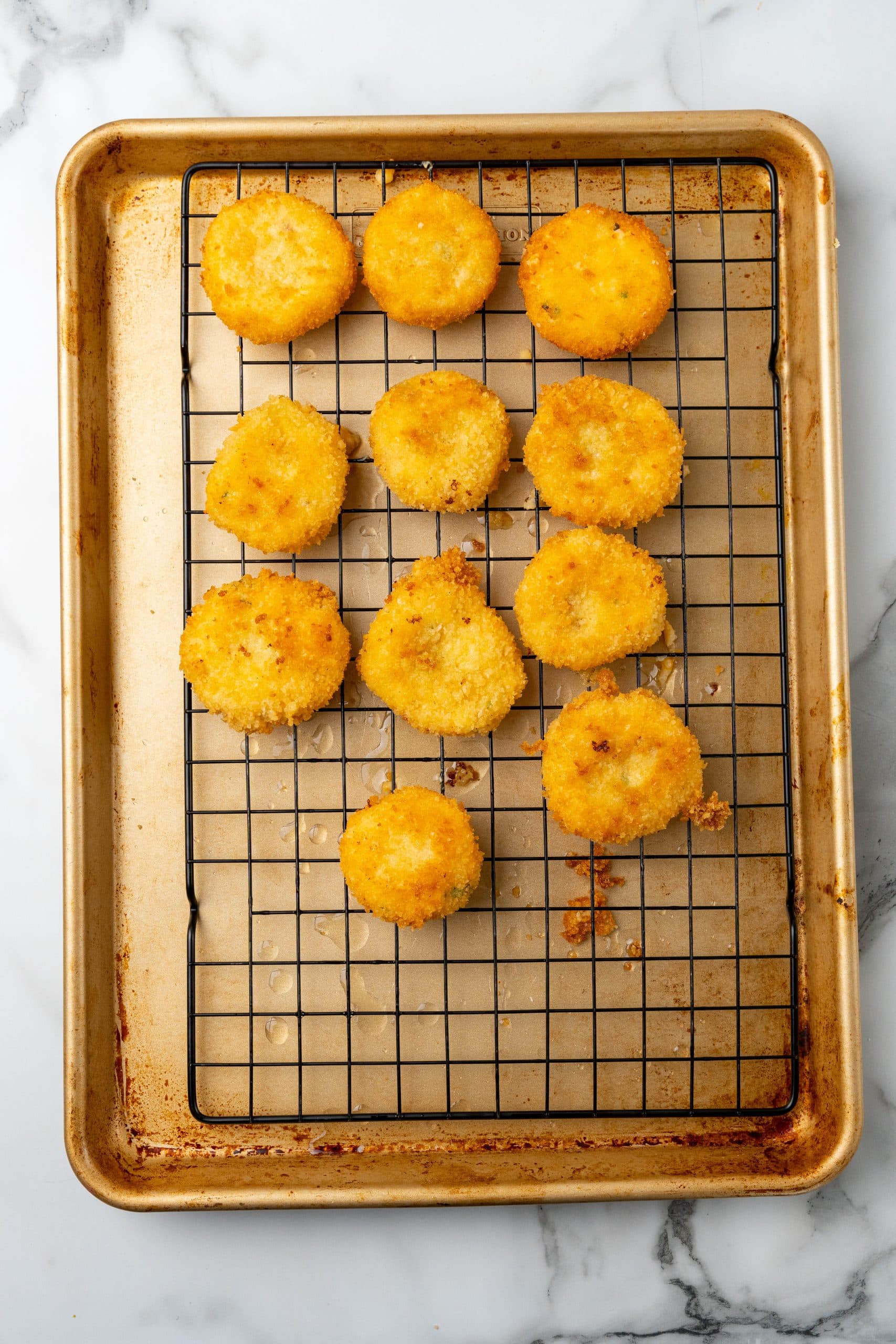 fried grits fritters draining on a wire rack over a metal sheet pan