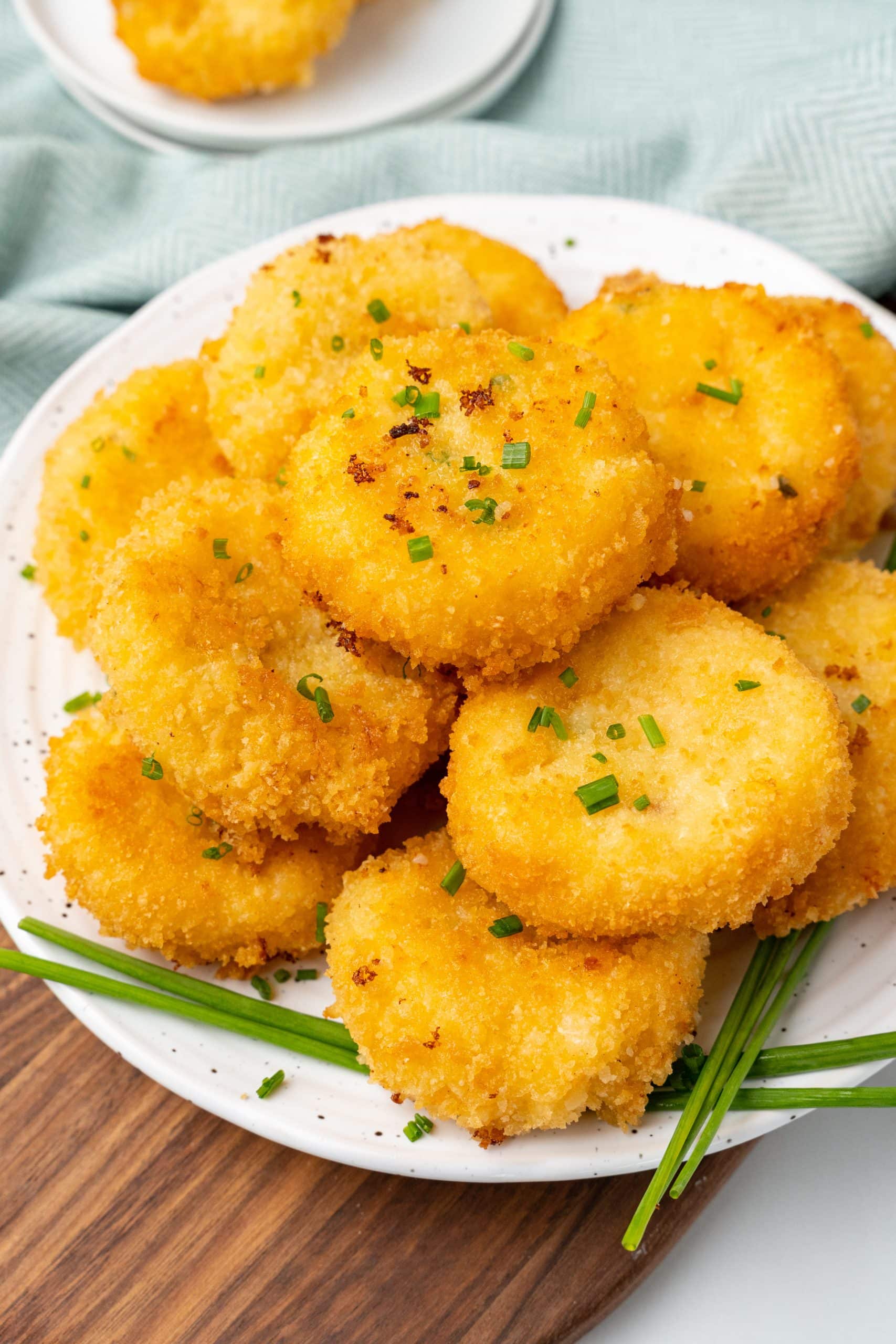 grits fritters piled on a white plate with chives on the side