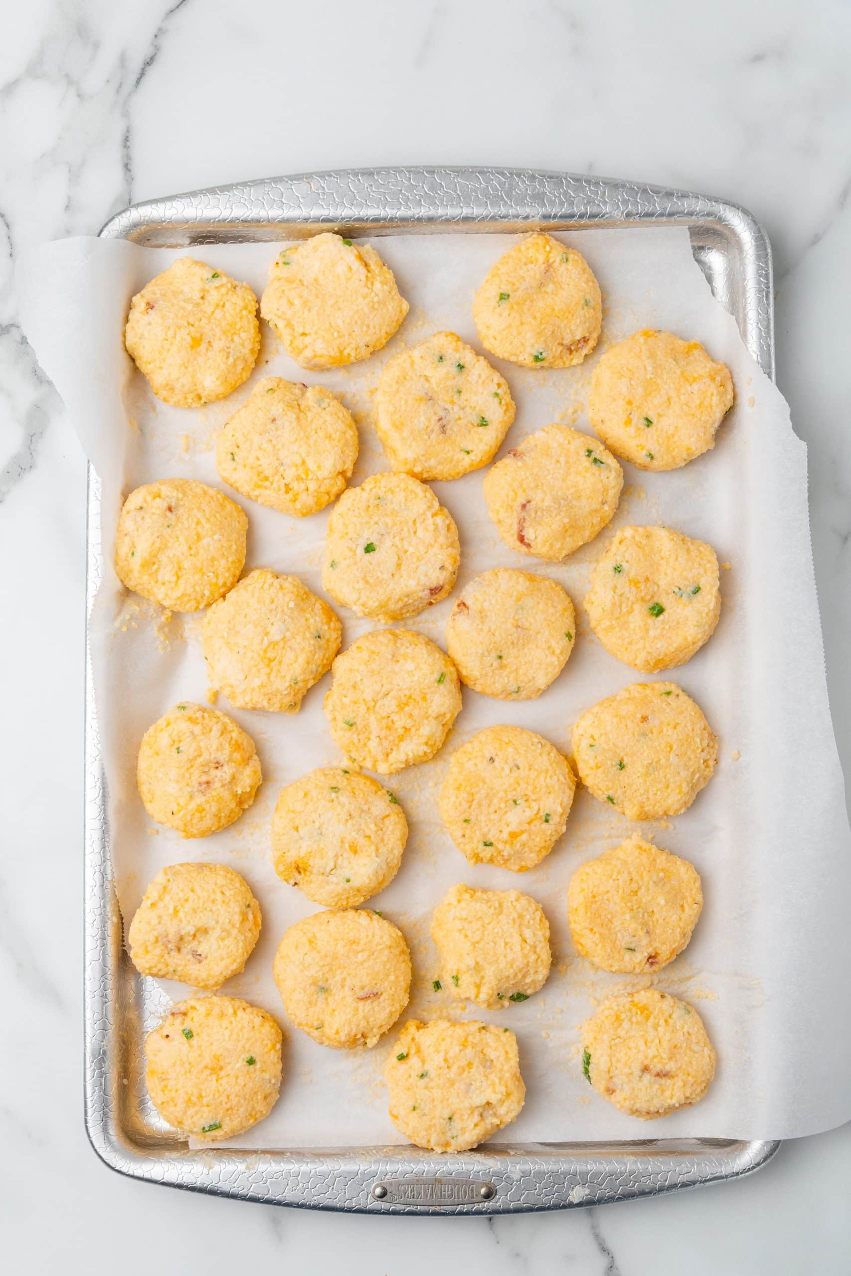 grits patties arranged in rows on a parchment paper lined sheet pan