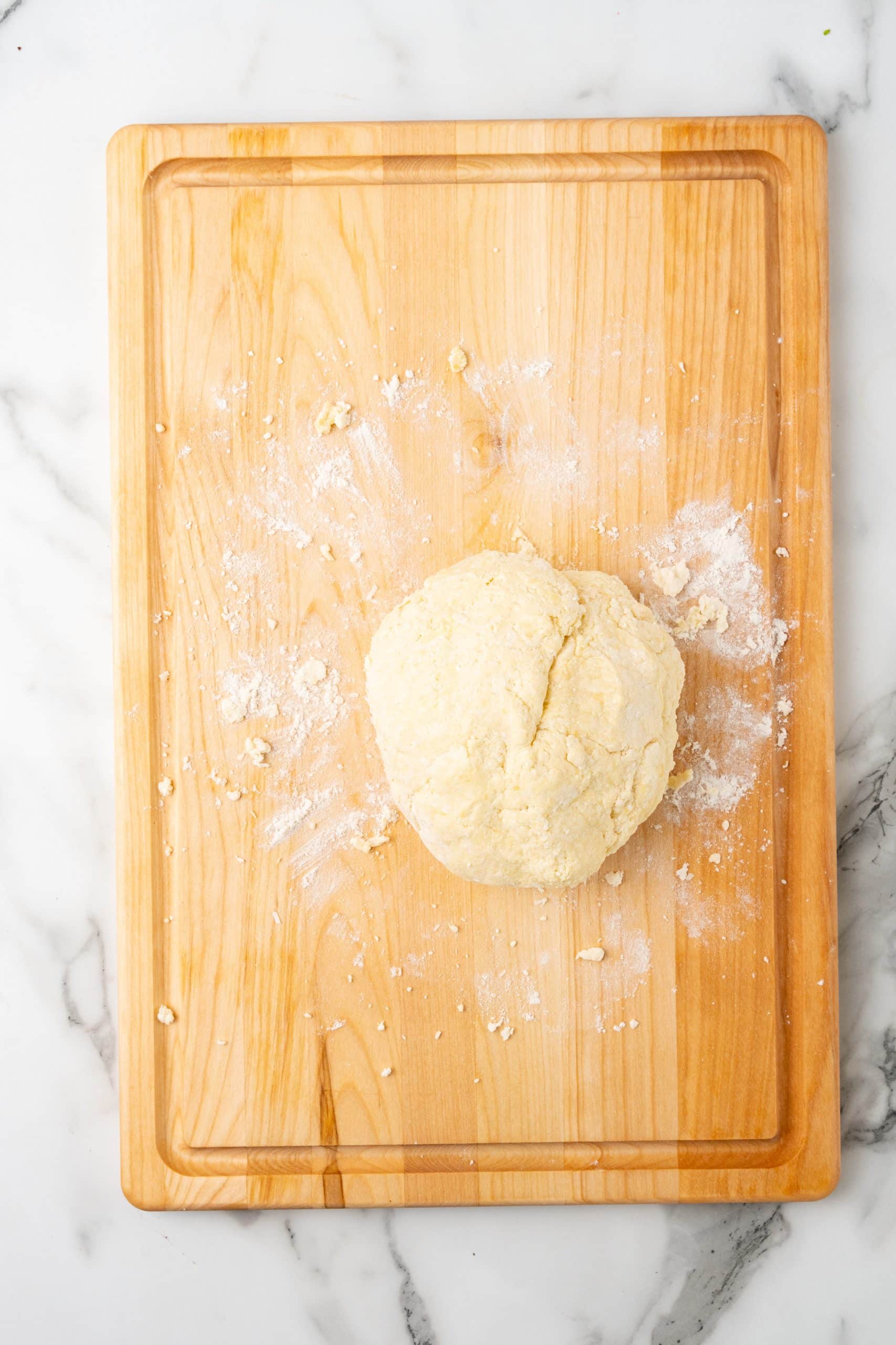 a ball of gnocchi dough on a floured wooden cutting board