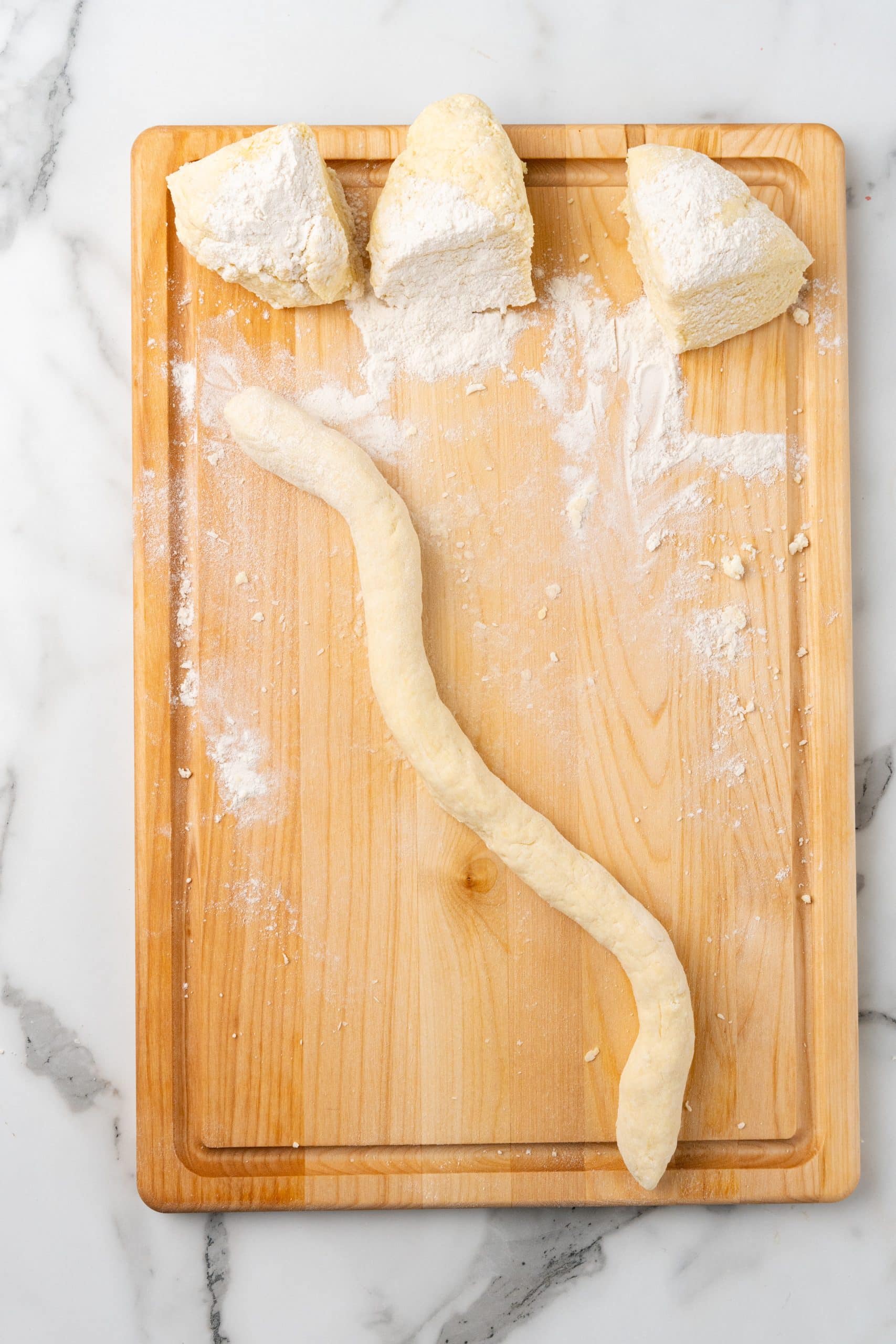 easy gnocchi dough rolled into a long rope on a floured wooden cutting board