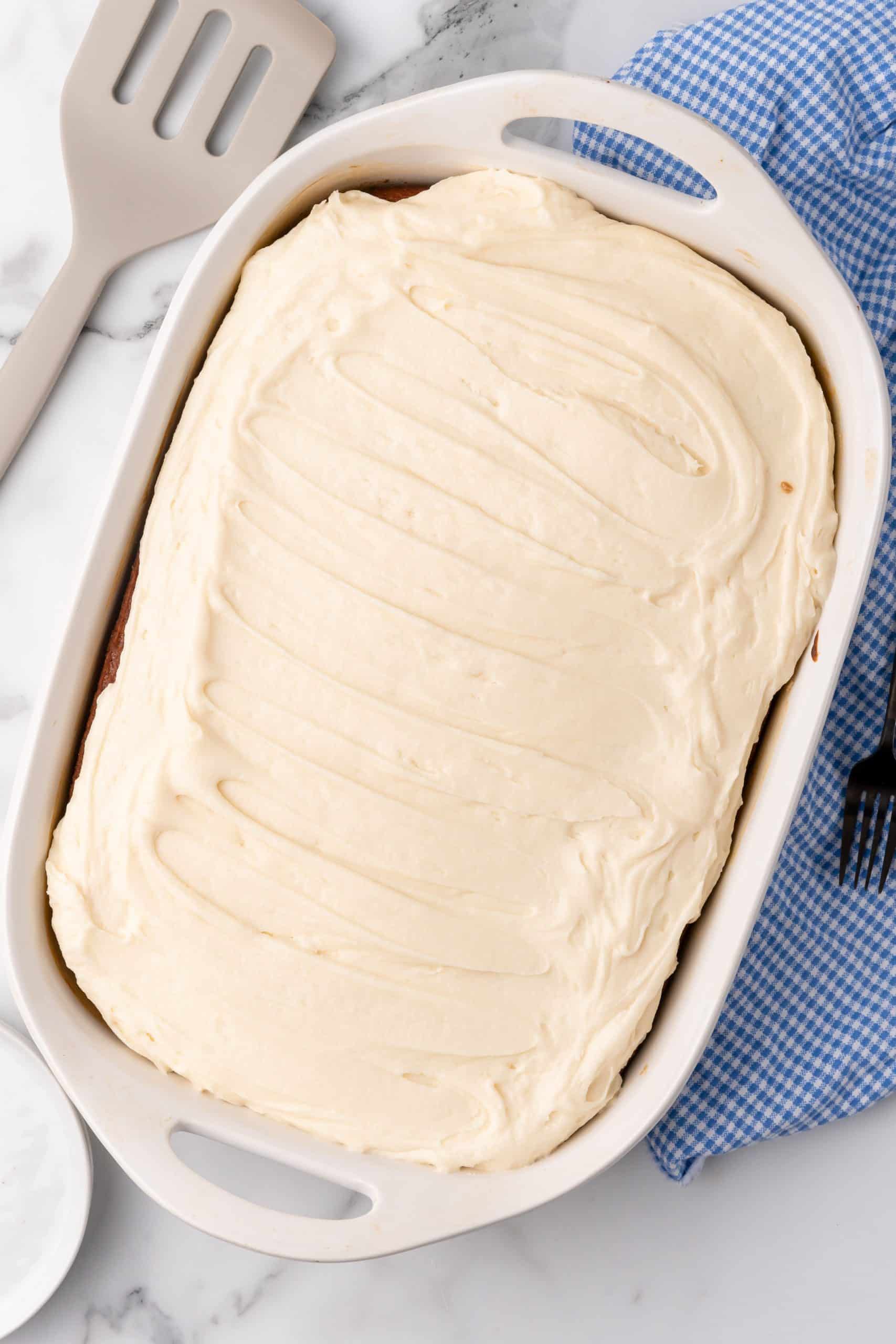 cream cheese icing frosted tomato soup cake in a white baking dish