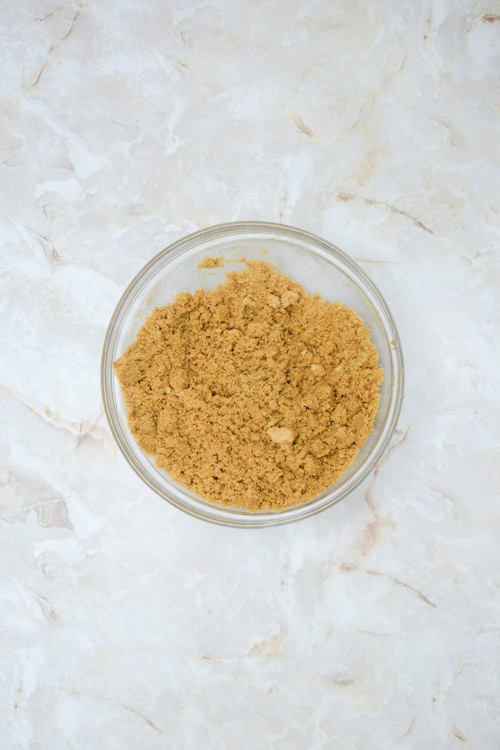 buttered graham cracker crumbs in a glass mixing bowl