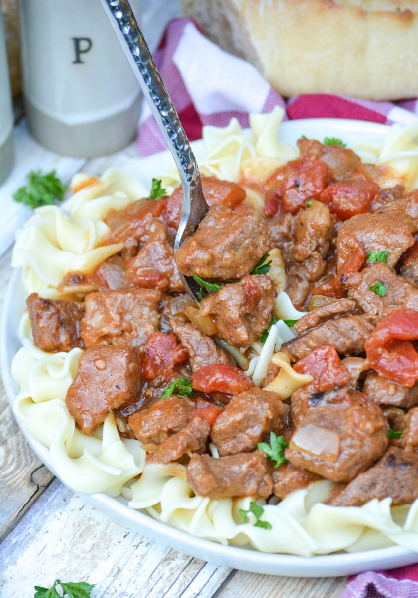Instant Pot Hungarian goulash over egg noodles on a white plate with a silver fork