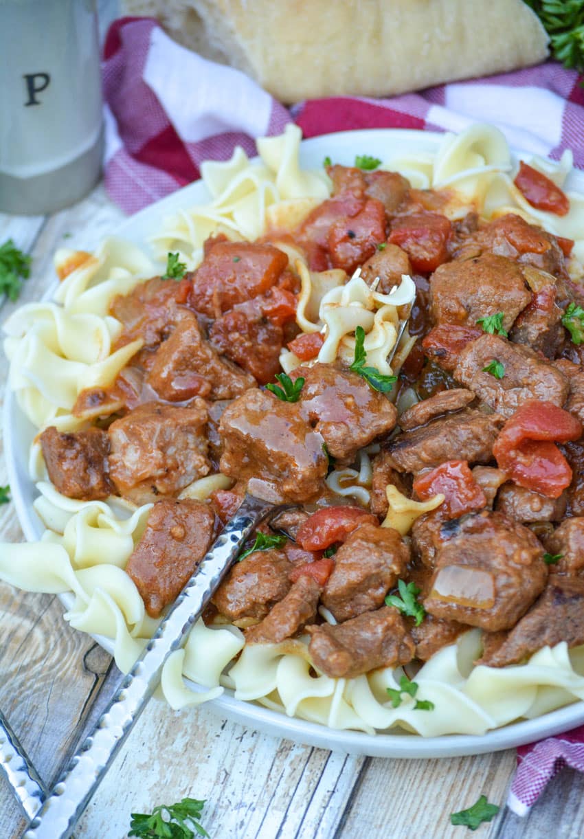 Instant Pot Hungarian goulash over egg noodles on a white plate with a silver fork