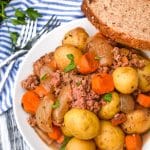 slow cooker corned beef hash in a white bowl with a slice of crusty bread on the side