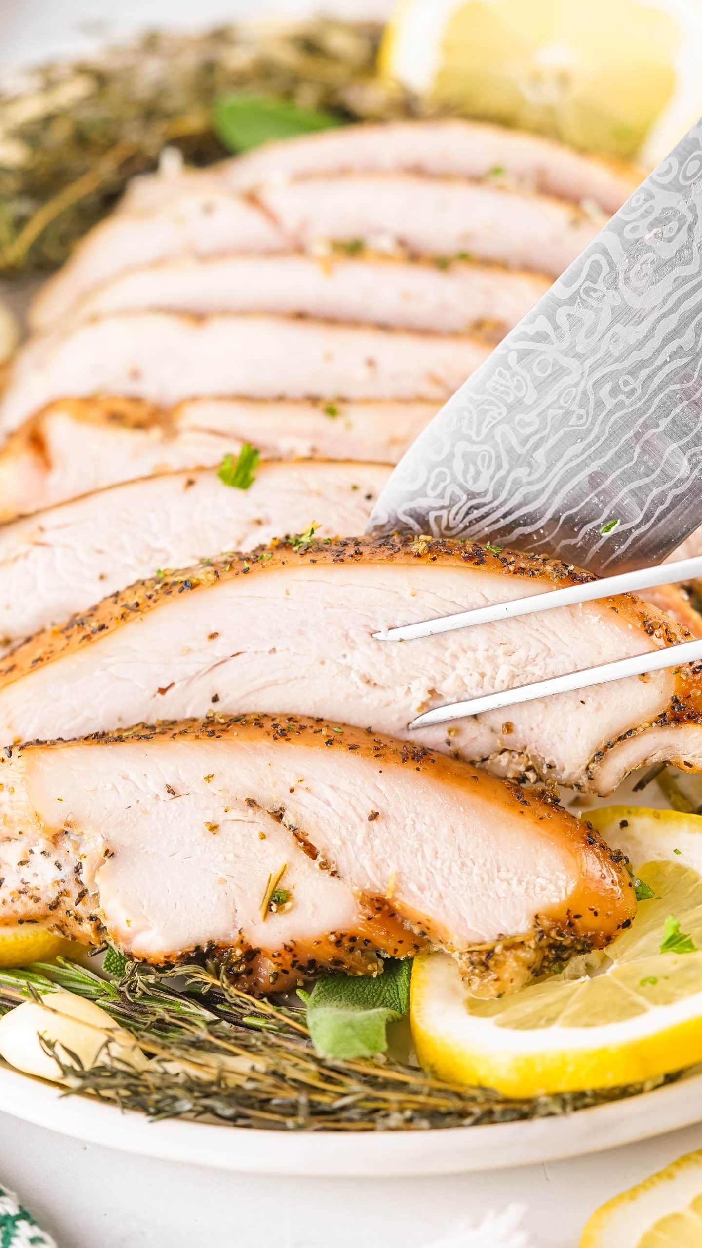 a knife and meat fork slicing a smoked turkey breast