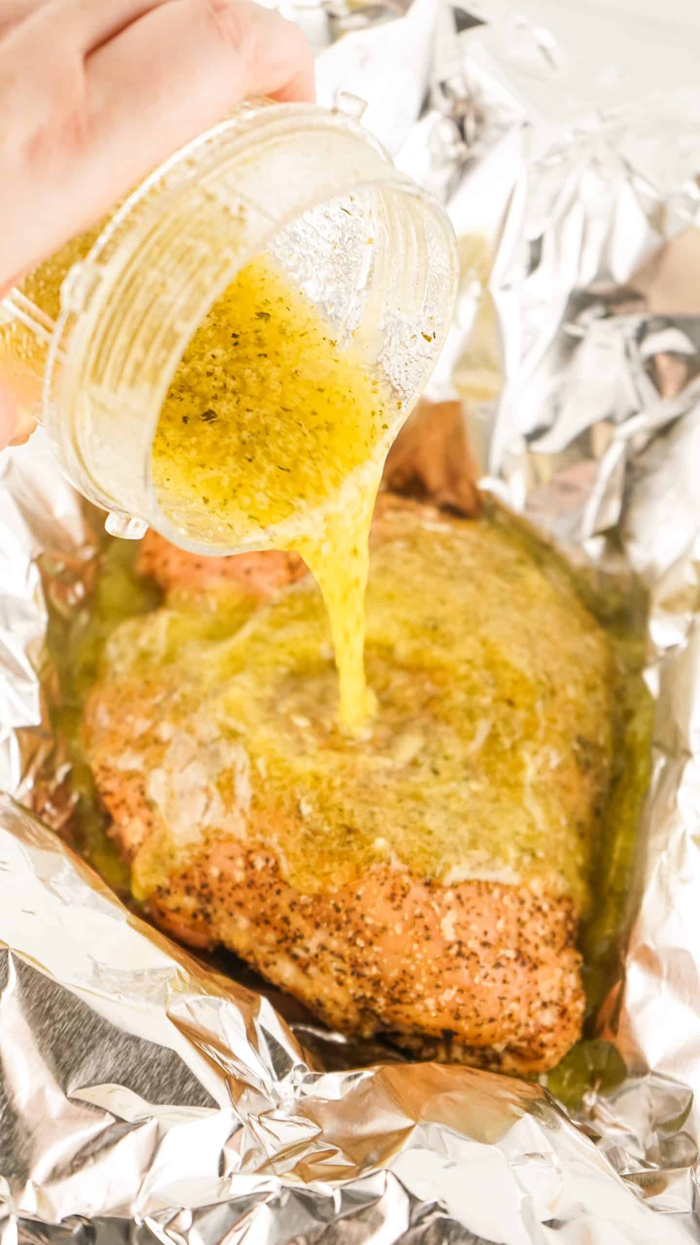seasoned butter and herbs being poured out over a smoked turkey breast from a glass jar