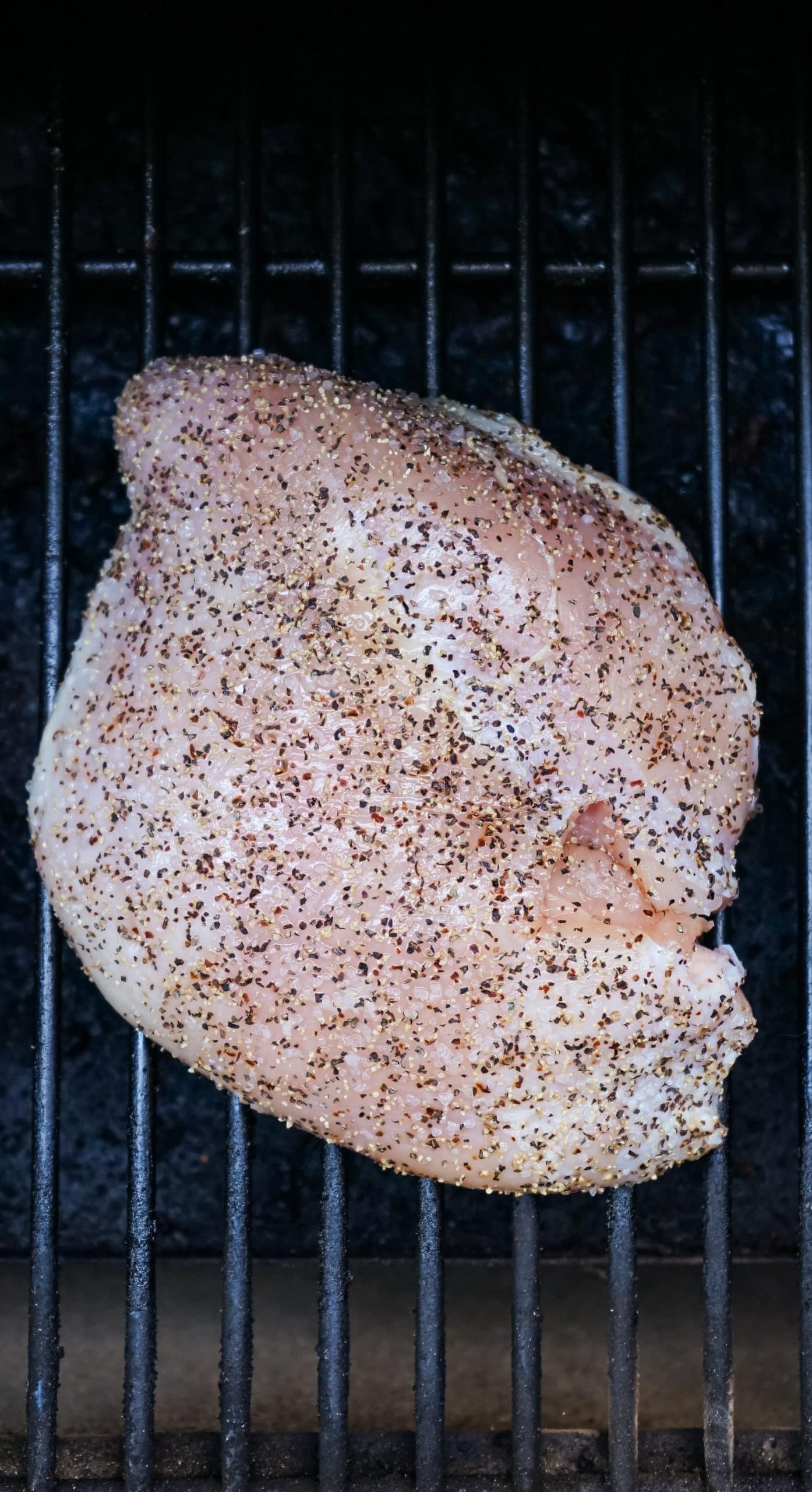 salt and pepper covered turkey breast on the grates of a smoker