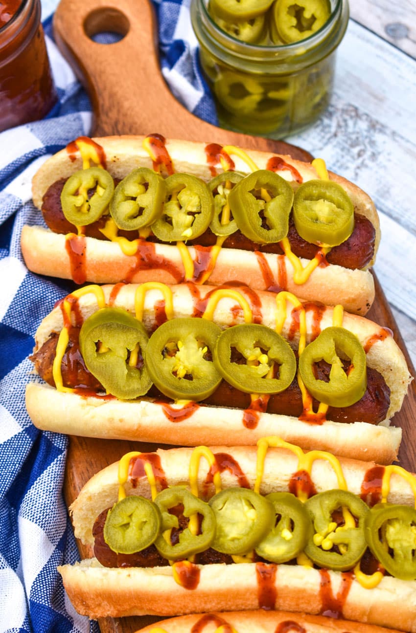 a row of smoked hot dogs on a wooden cutting board