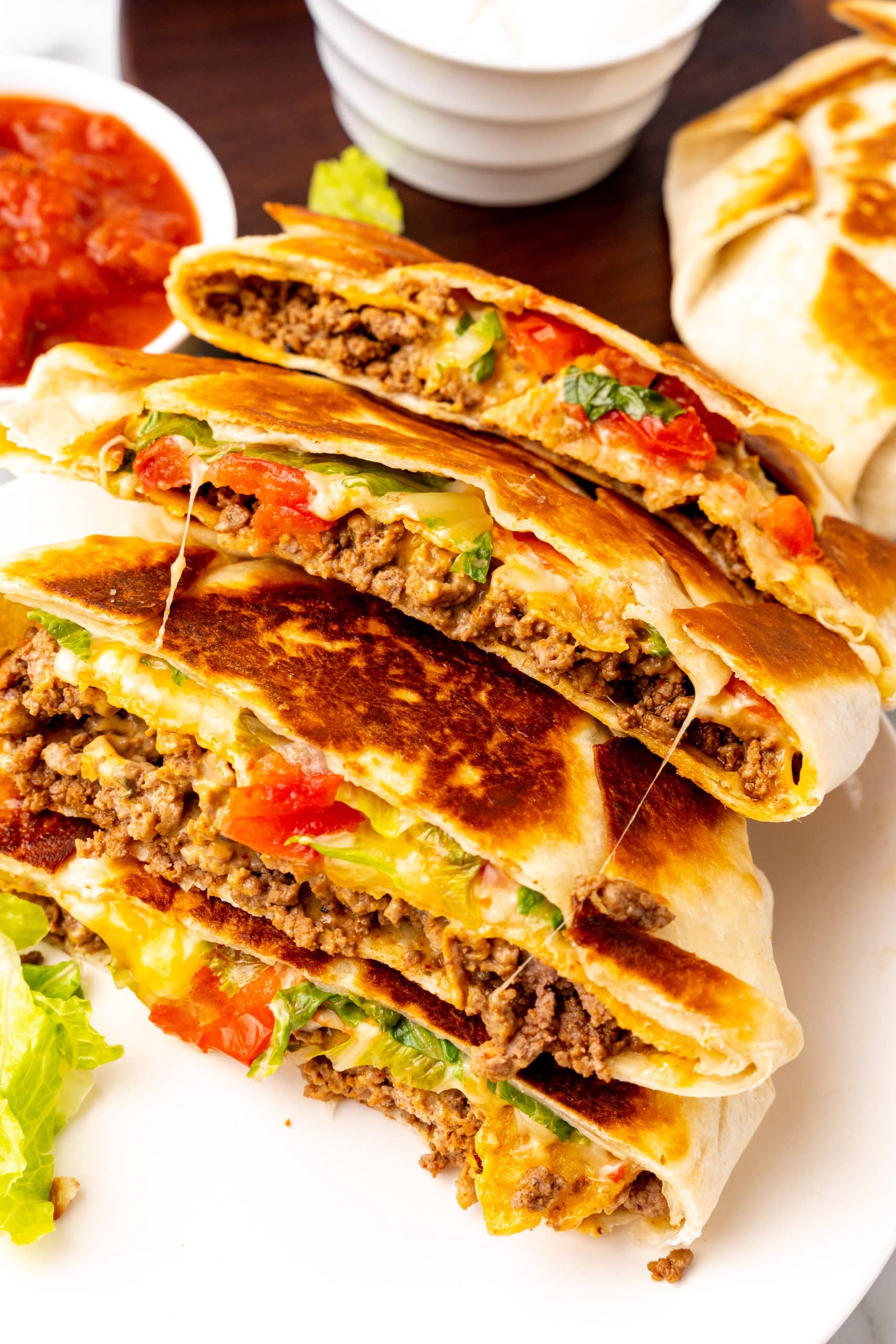 a stack of halved crunchwrap supreme sandwiches on a white plate