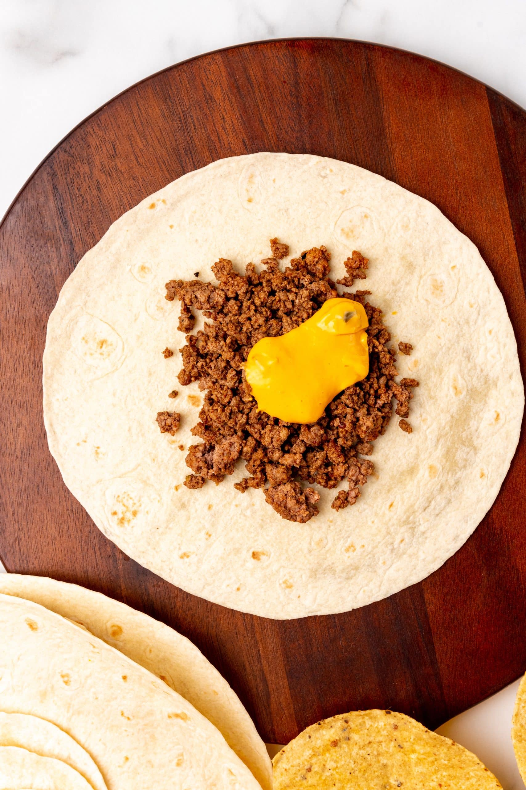 queso topped ground beef on a large flour tortilla