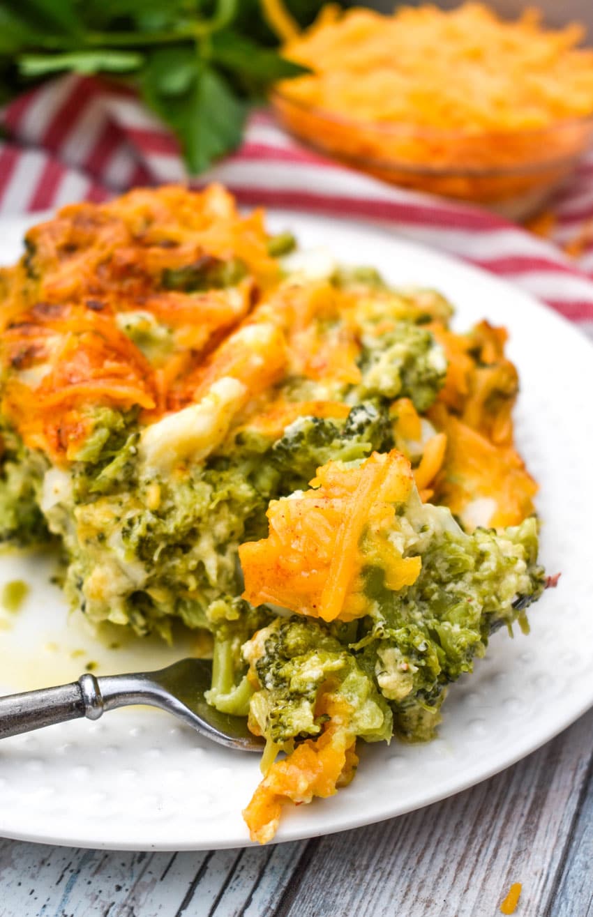 cheesy broccoli souffle casserole on a white plate with a silver fork on the side