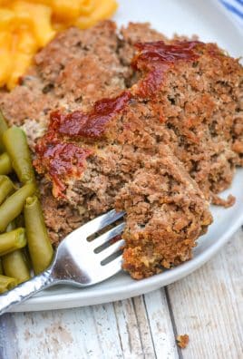 a silver fork on a white dinner plate with a slice of easy homemade meatloaf