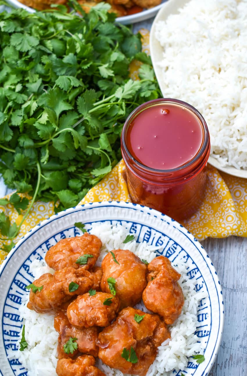 easy sweet and sour chicken over steamed white rice in a white and blue bowl