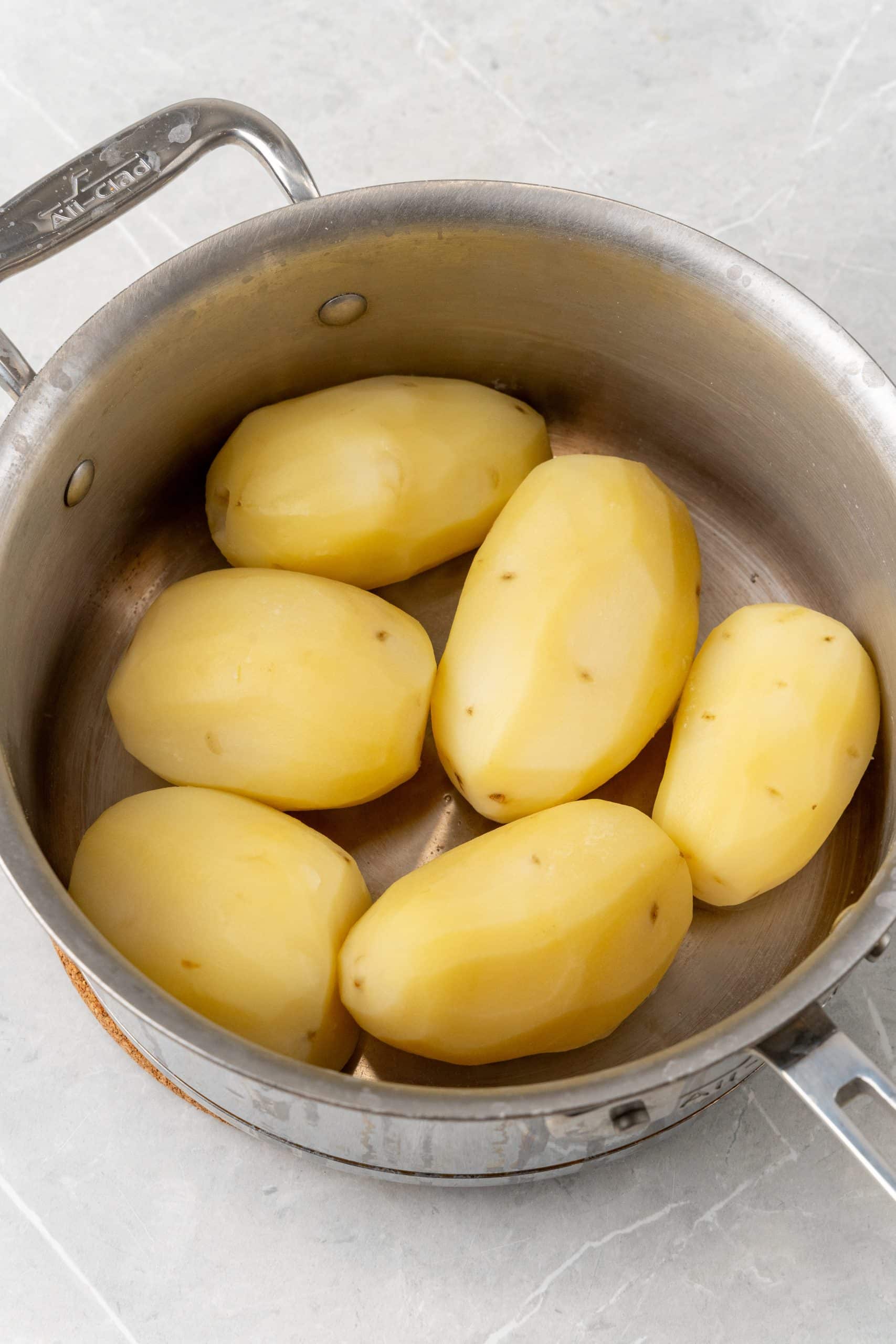 peeled potatoes in a large silver pot