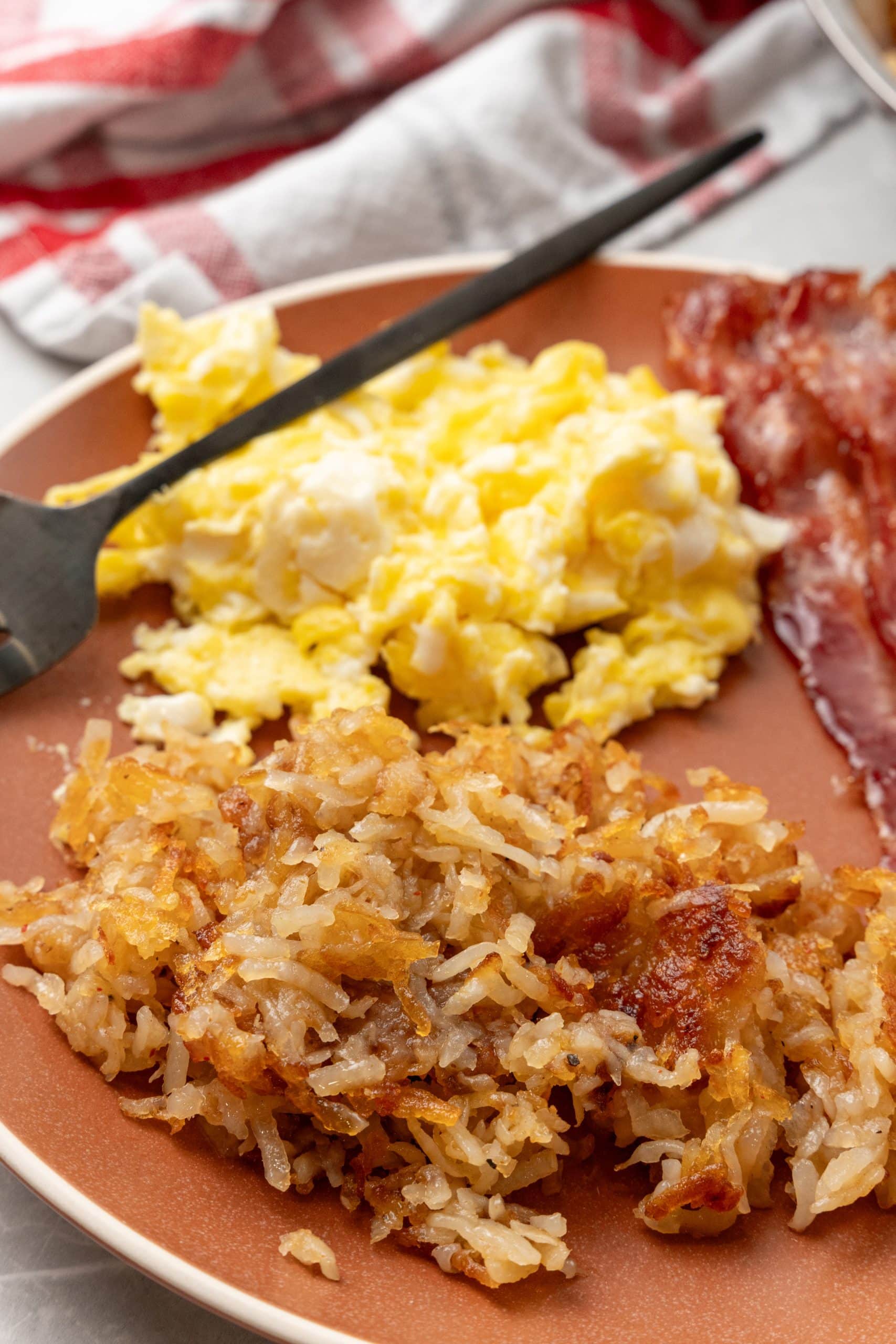 easy homemade hash browns on a brown plate with a side of eggs and bacon