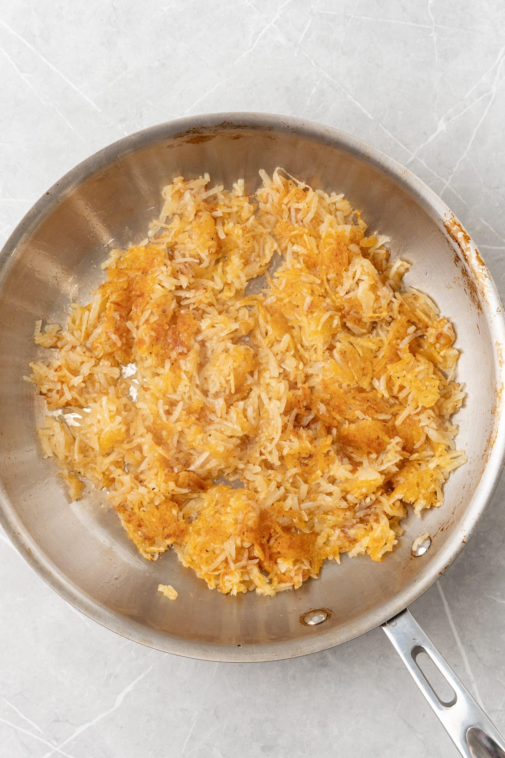 golden crispy homemade hash browns in a silver skillet