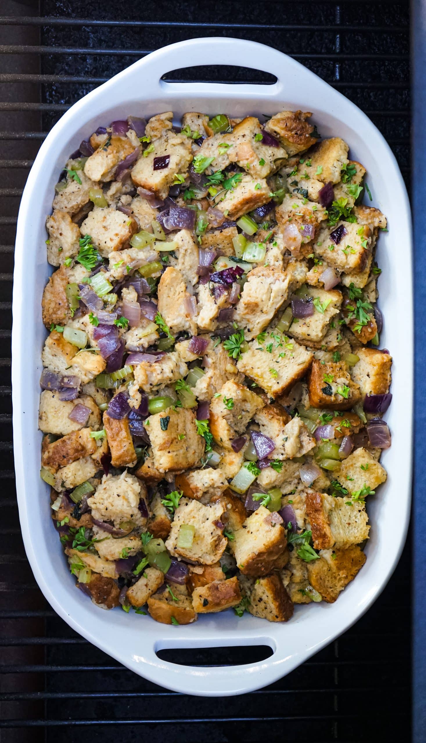 smoked stuffing recipe in a white baking dish on the grates of a grill