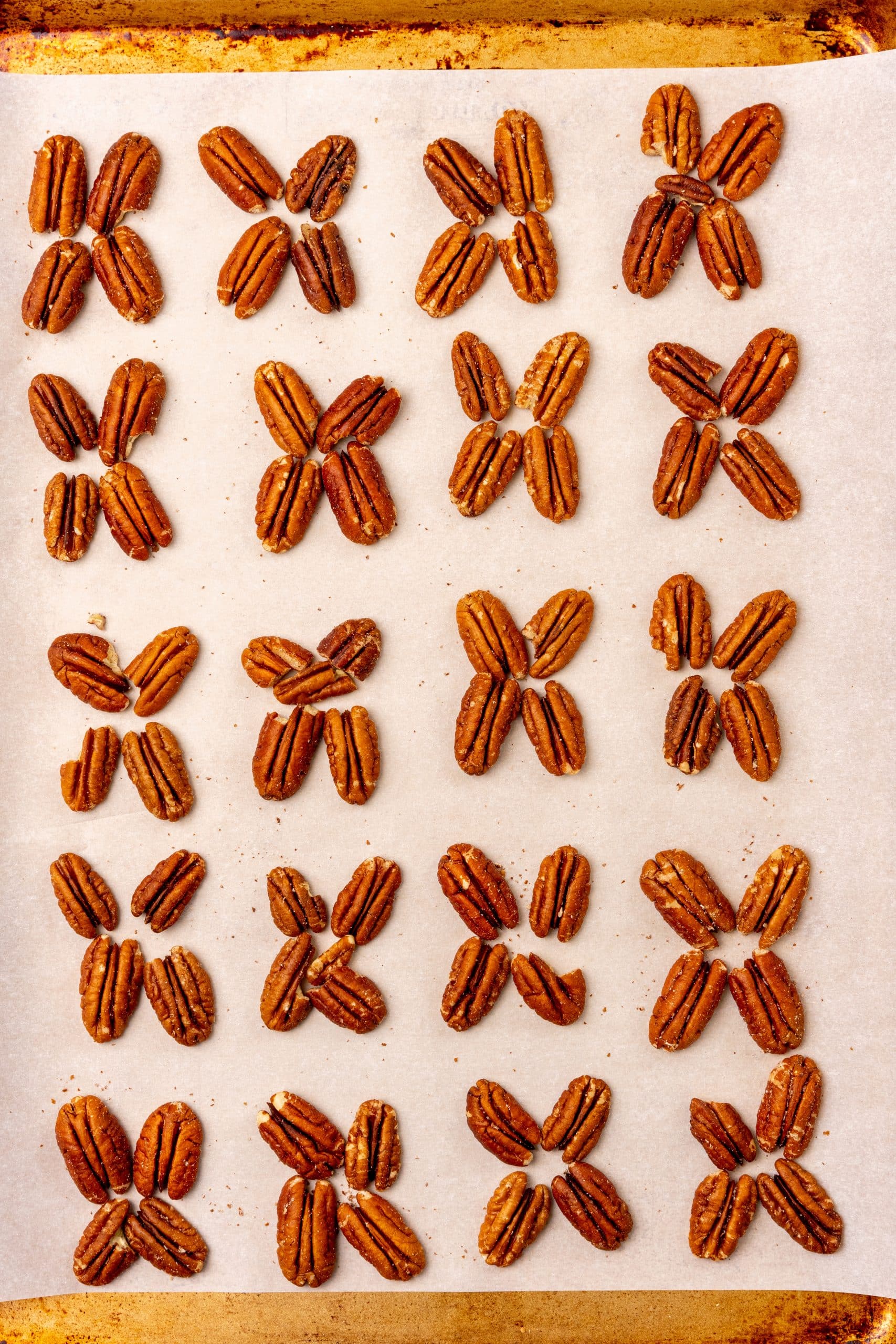 pecan halves arranged in an x pattern on a parchment lined baking sheet