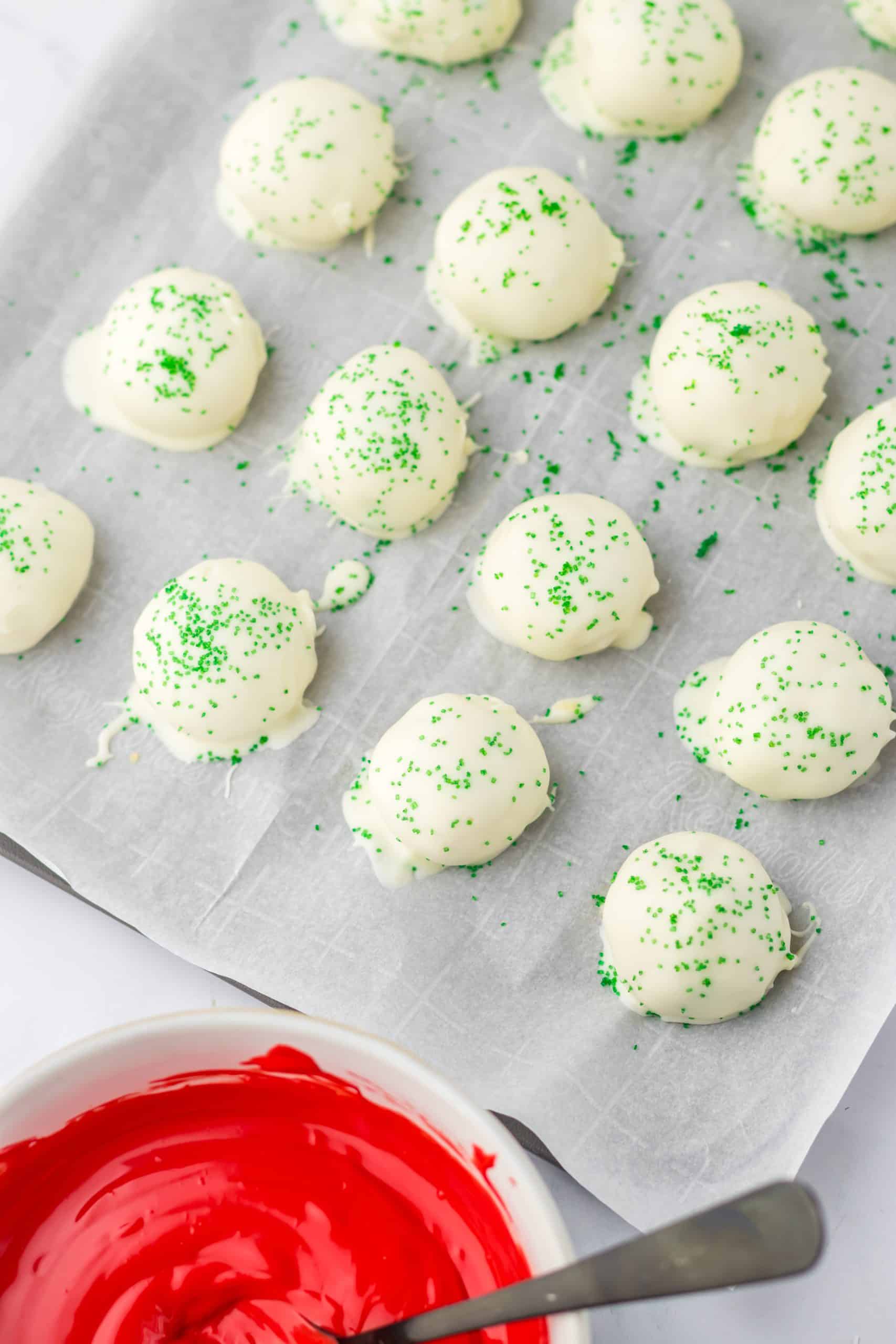 white chocolate covered cake balls with green sprinkles on top