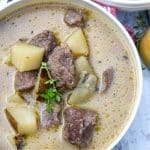 creamy steak and potato soup in a white bowl