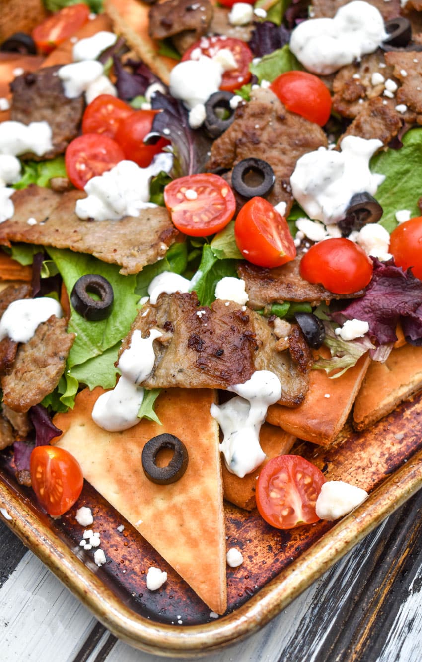 loaded gyro nachos with homemade pita chips on a metal baking pan