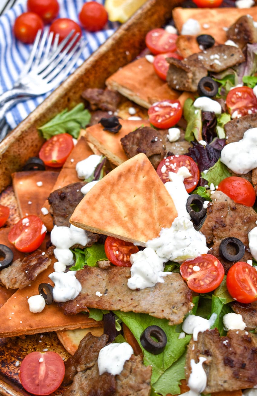 loaded gyro nachos with homemade pita chips on a metal baking pan