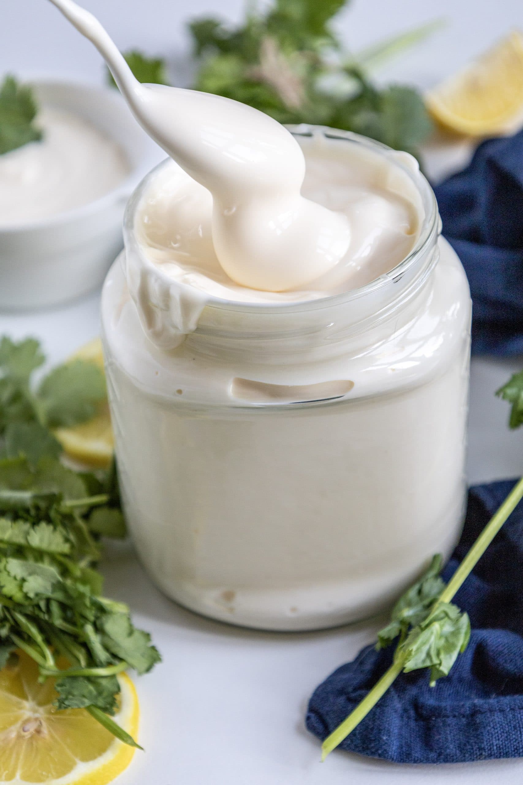 a silver spoon scooping homemade mayonnaise out og a glass jar