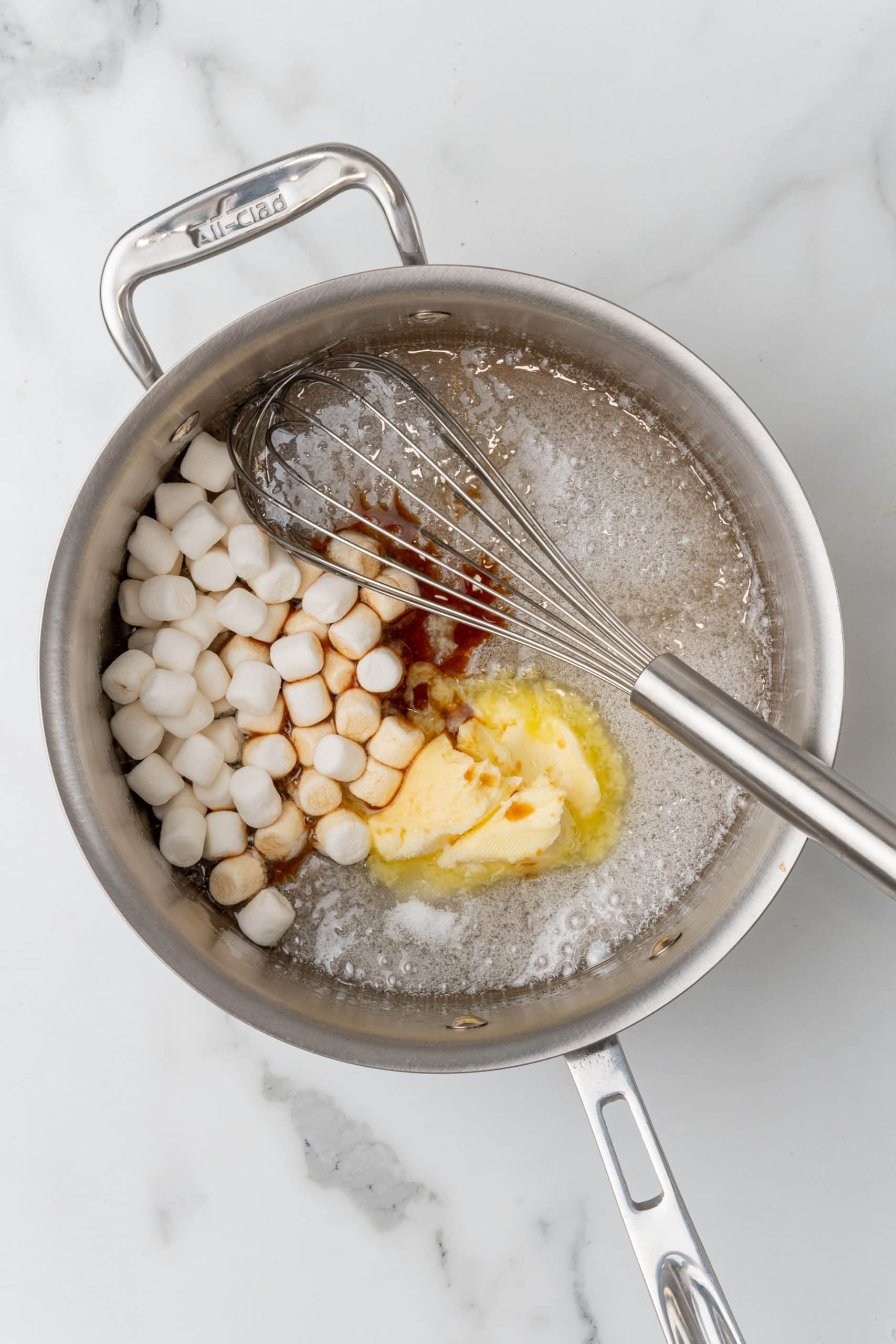 marshmallow syrup ingredients in a silver sauce pan with a wire whisk