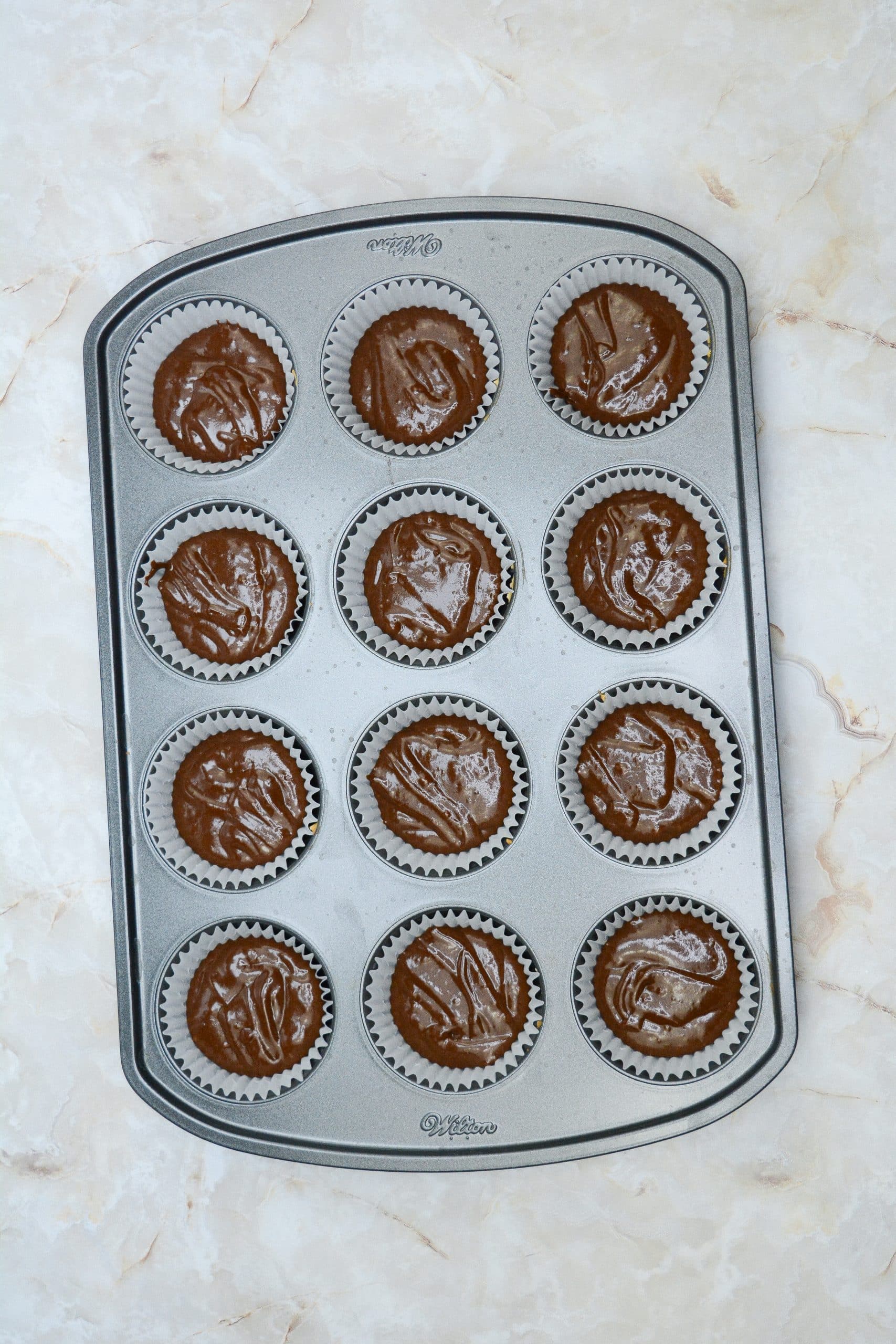 homemade chocolate cupcakes batter in a paper lined metal muffin tin