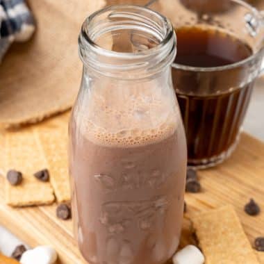 s'mores coffee creamer in a small glass jar sitting on a wooden cutting board