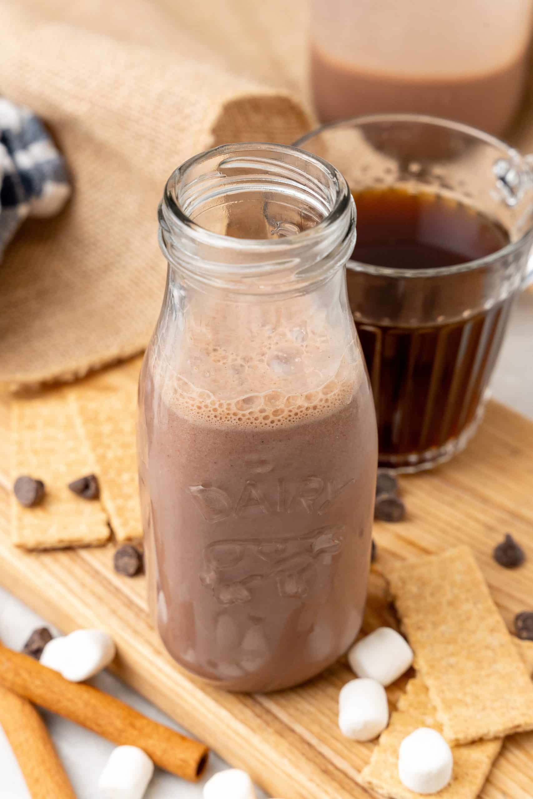 s'mores coffee creamer in a small glass jar sitting on a wooden cutting board