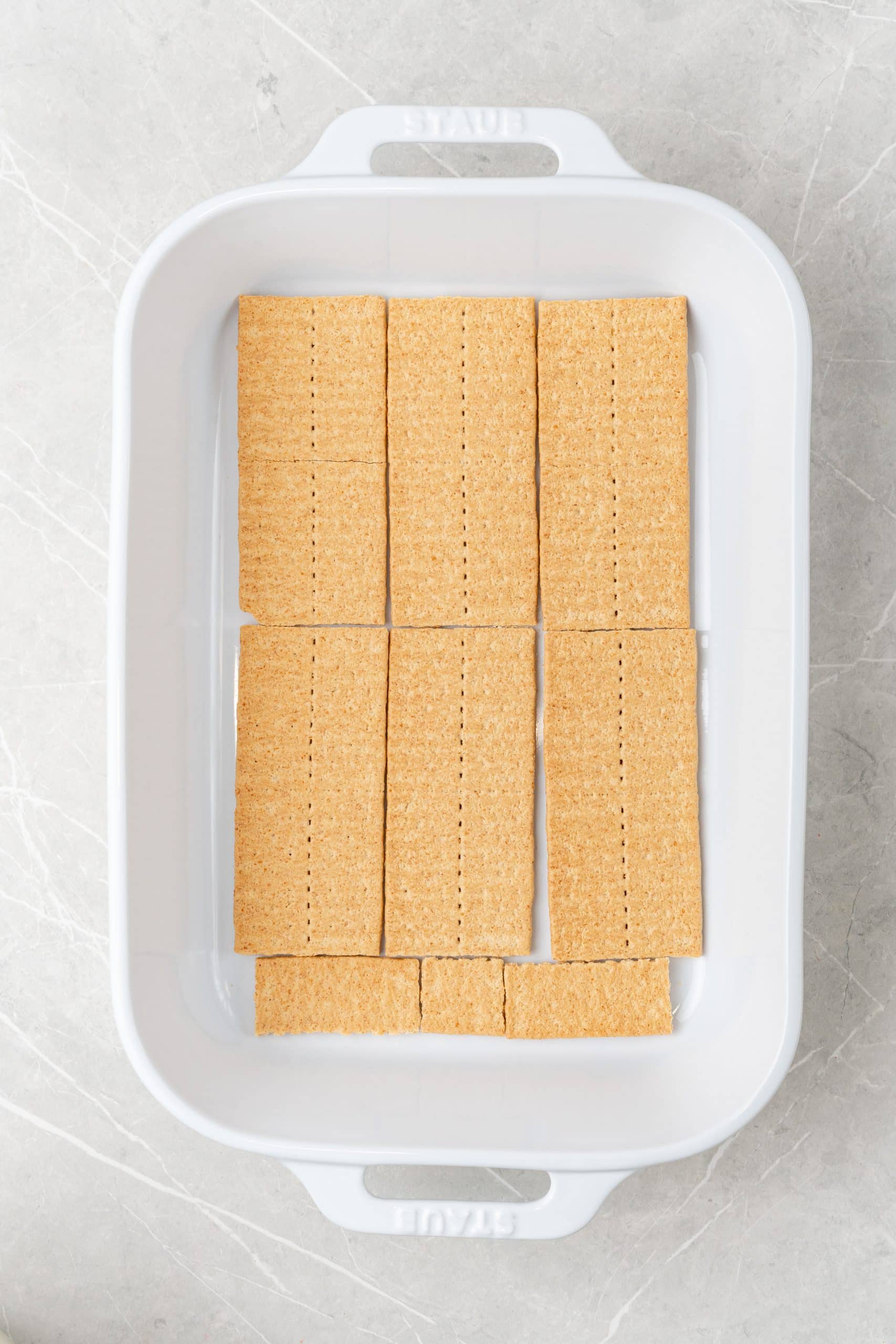 graham crackers lining the bottom of a white baking dish