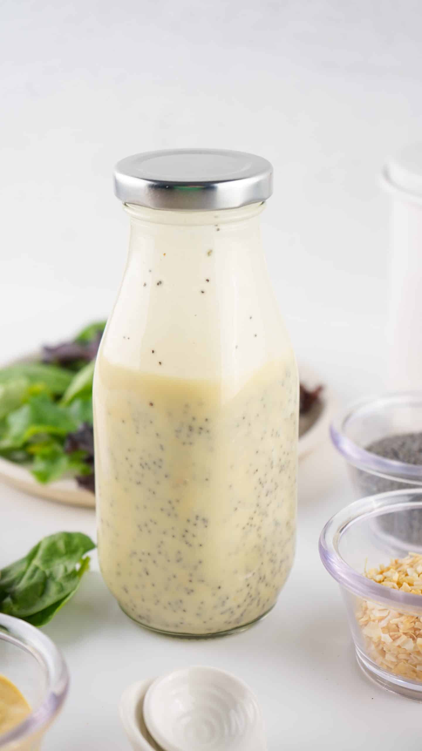 homemade poppy seed dressing recipe in a glass jar with a place of salad in the background