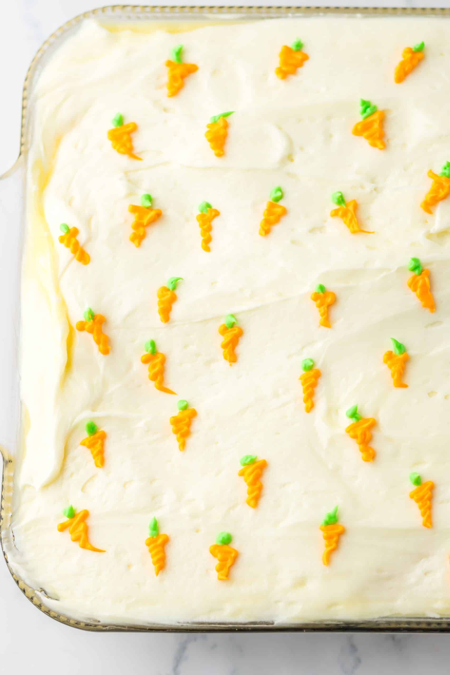 a decorated carrot cake poke cake in a 9x13 inch glass baking dish