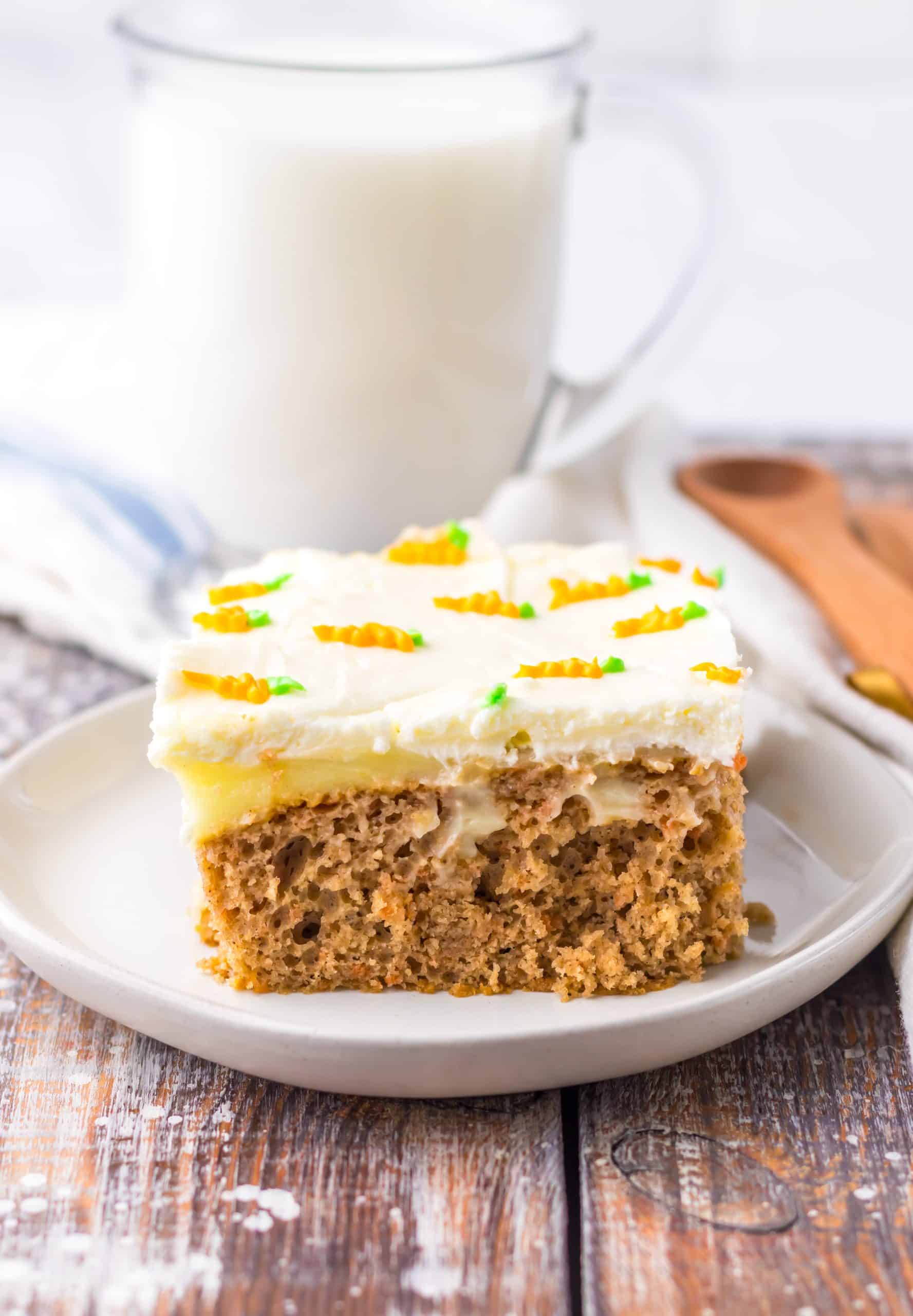 a slice of carrot cake poke cake on a small white dessert plate with a glass of milk in the background