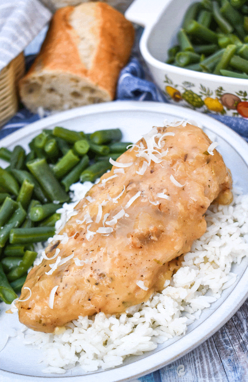 a piece of instant pot lemon chicken over steamed white rice on a gray plate with green beans on the side