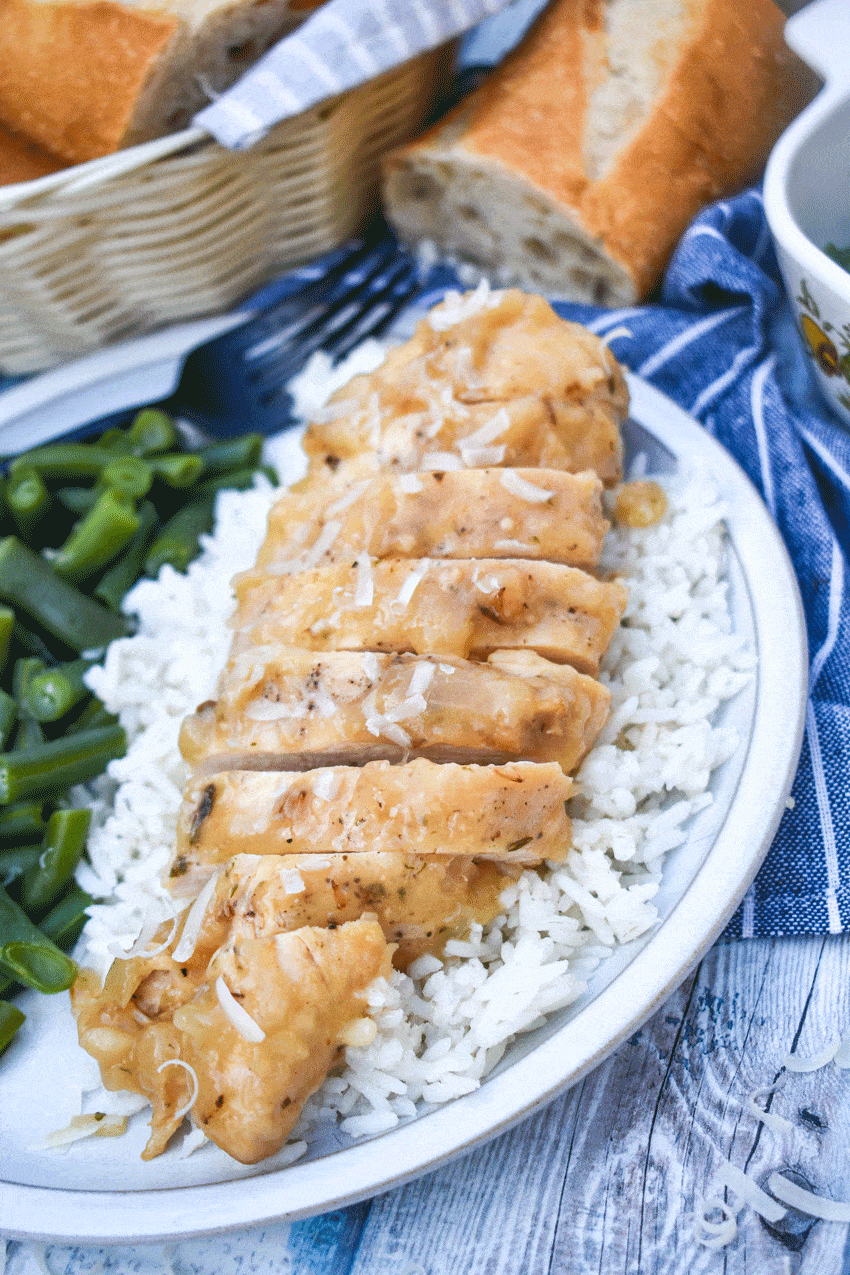 a sliced piece of instant pot lemon chicken over steamed white rice on a gray plate with green beans on the side