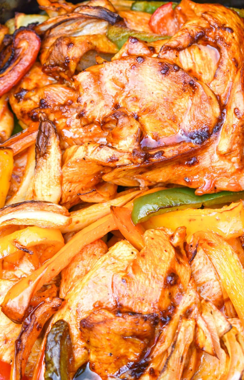 a close up of fajita chicken with peppers and onions in an air fryer basket
