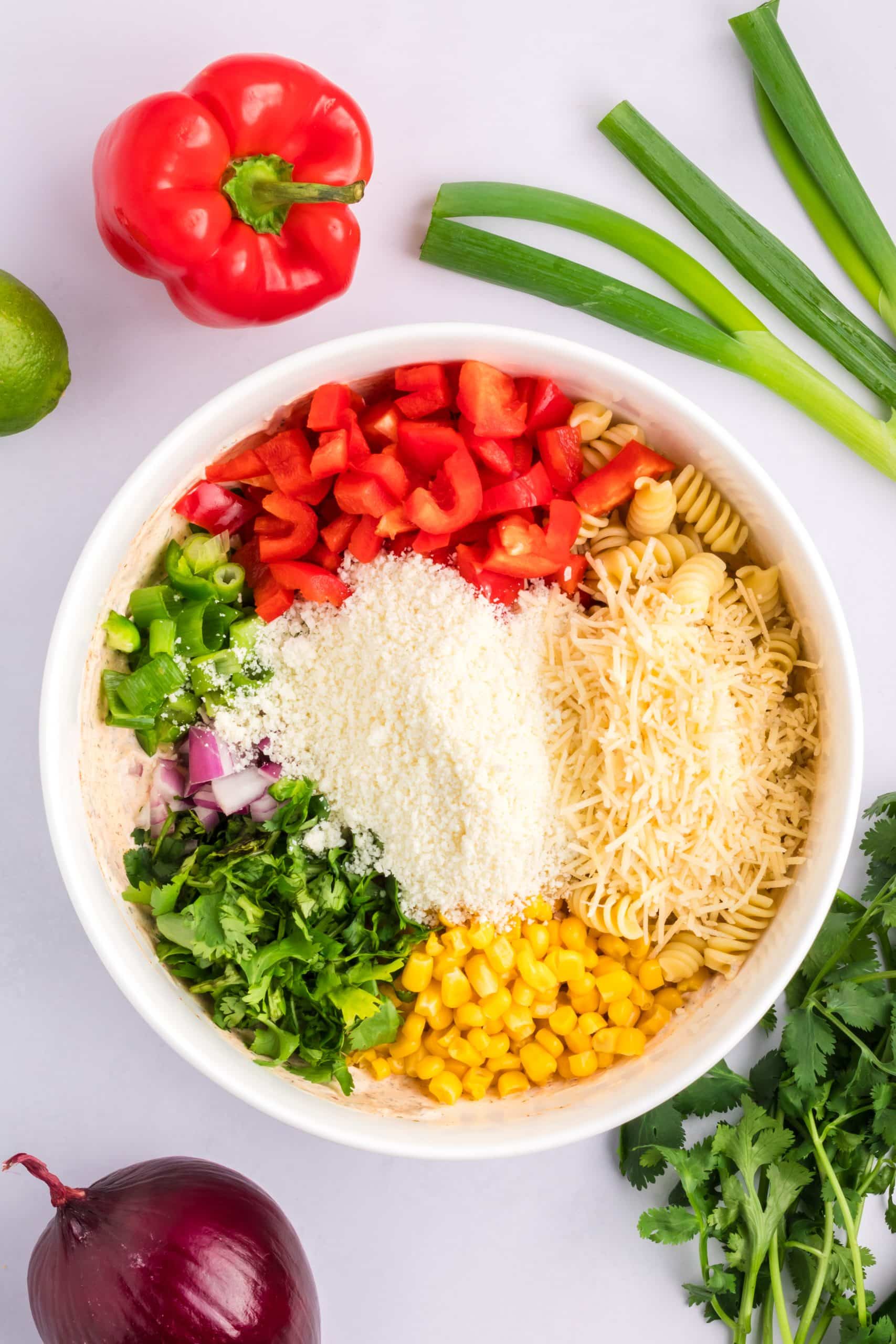 mexican street corn pasta salad ingredients in a large white bowl