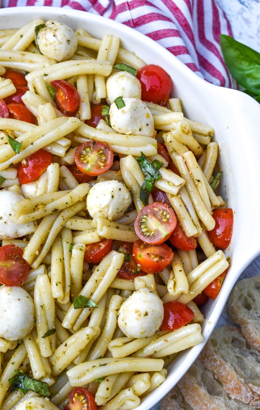 a close up of caprese pasta salad in a large white serving bowl