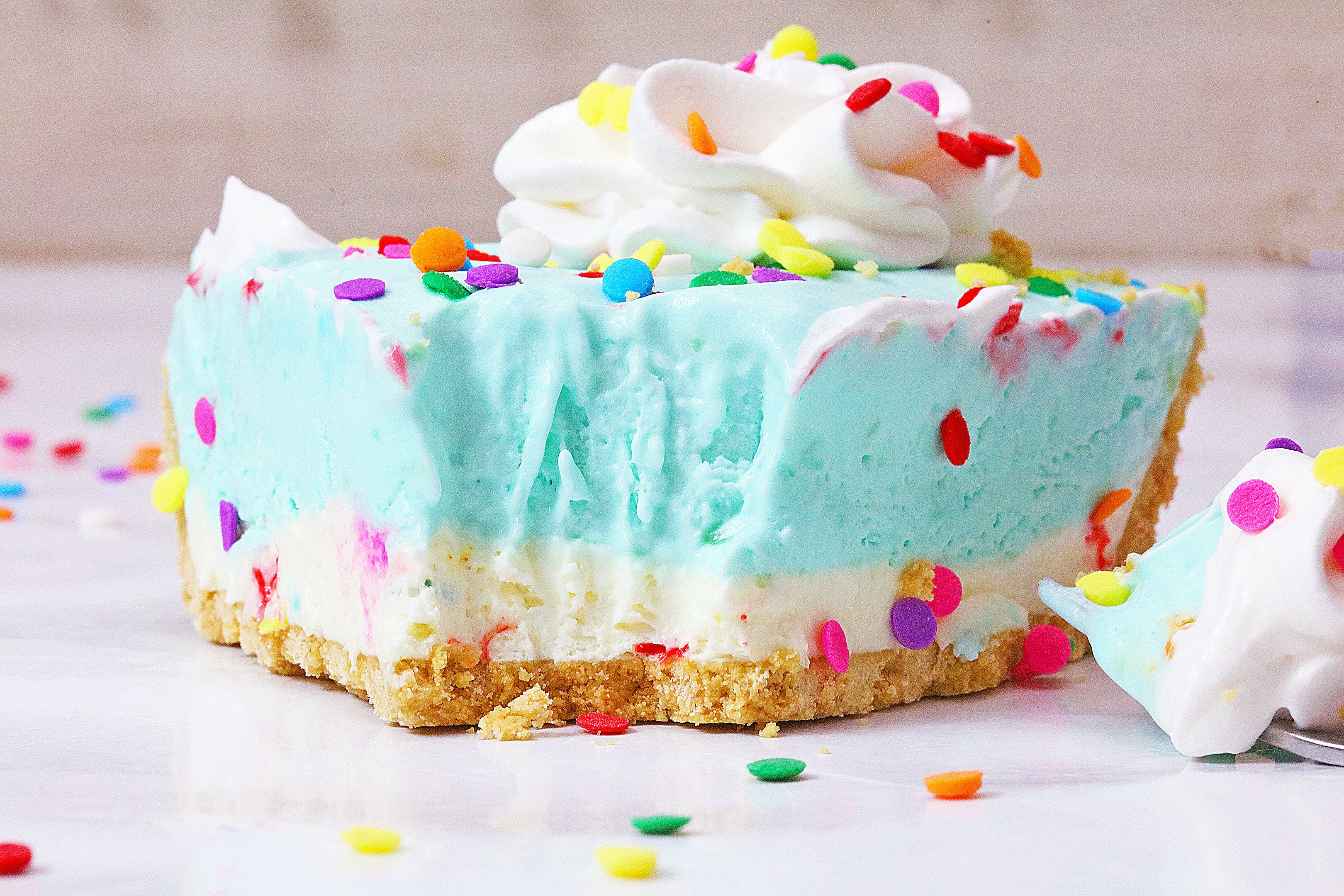 a closeup of a slice of no bake cake batter pie on a marble countertop surrounded by sprinkles