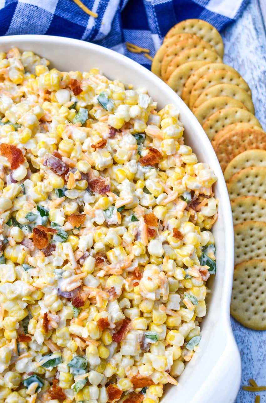 jalapeno popper grilled corn salad in a large white serving bowl with crackers on the side