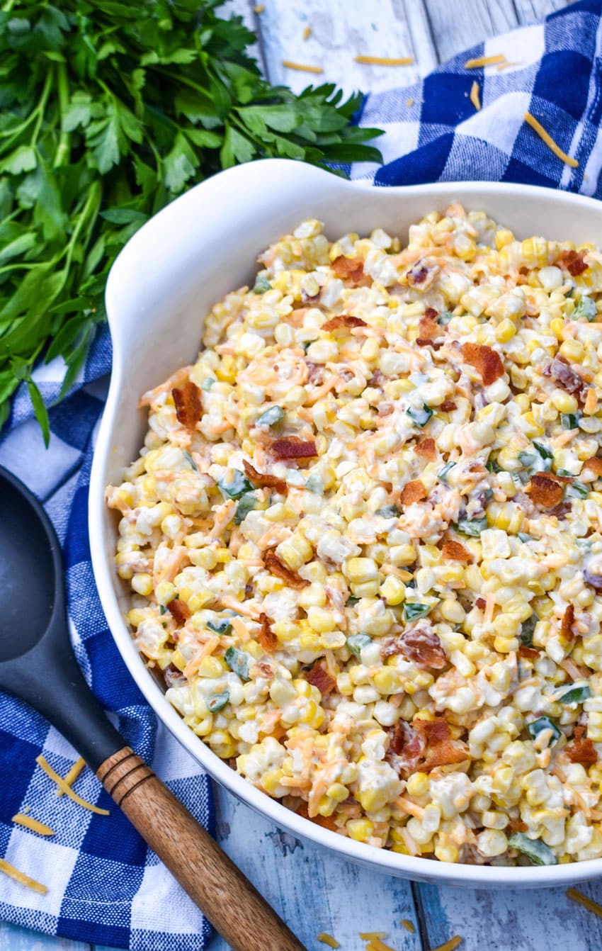 jalapeno popper grilled corn salad in a large white serving bowl with fresh herbs on the side