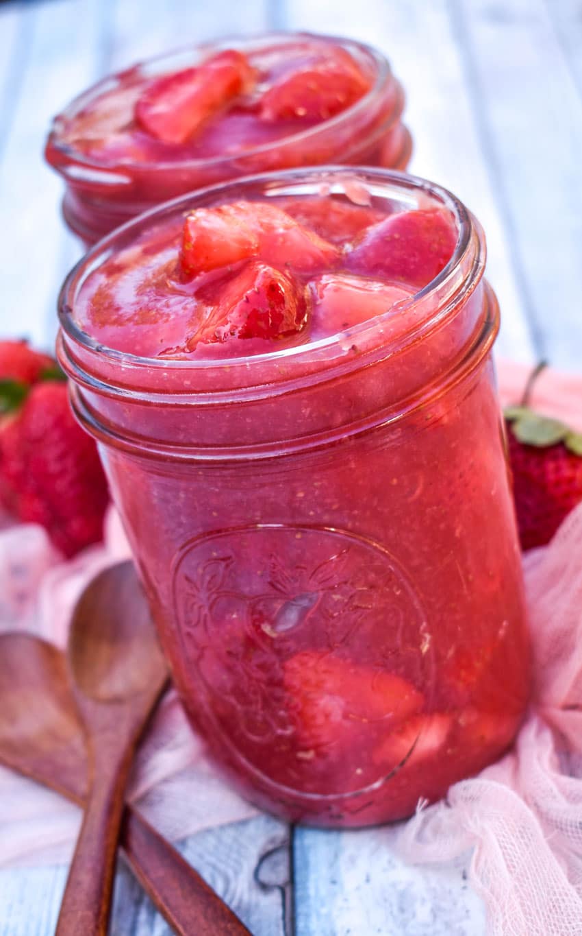 strawberry pie filling in two glass jars on a wooden table