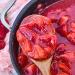 a wooden spoon holding up a scoop of homemade strawberry pie filling