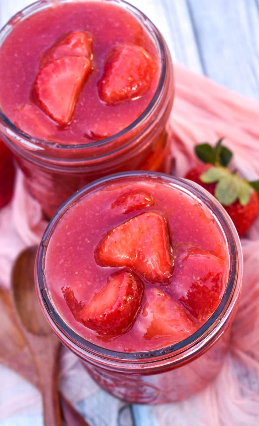 strawberry pie filling in two glass jars on a wooden table